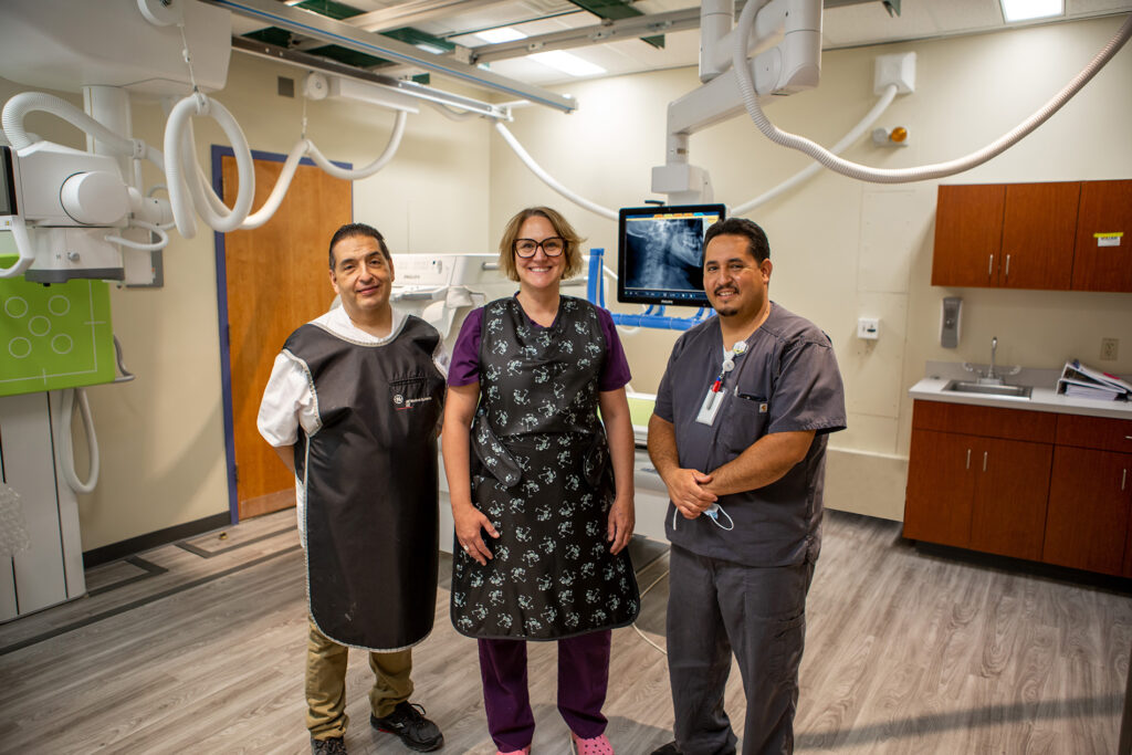 Troy Martinez, Tracey Poffenroth Prato, and Marcos Romero standing with the video flouroscopy equipment at Holy Cross Hospital