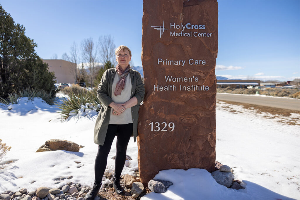 Dr. Mary Jo Young, Primary Care Doctor standing next to a large stone sign for the primary care office.