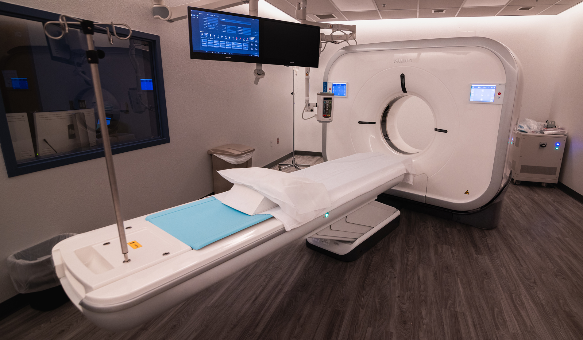 Modern CT scan room featuring a scanning machine, patient bed, and monitors, designed for advanced medical imaging.