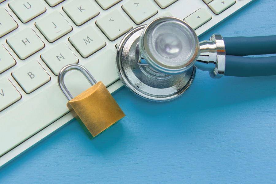 A stethoscope and a padlock rest on a computer keyboard, symbolizing health and security in digital environments.