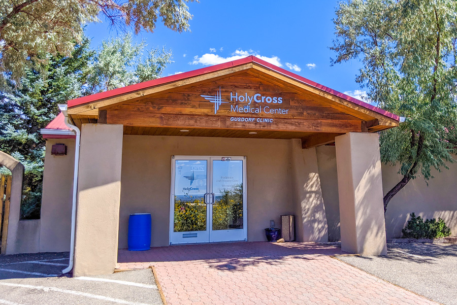 Holy Cross Medical Center entrance featuring a wooden awning and clear signage, surrounded by greenery.